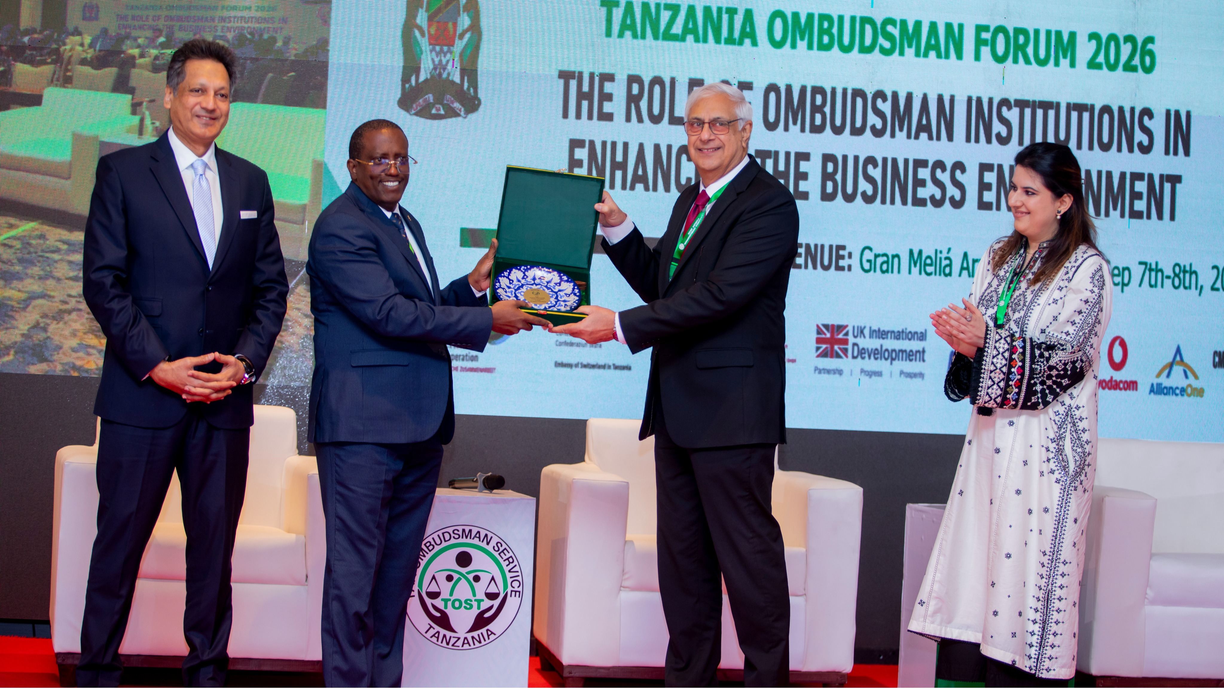 Kaimu wa Kitengo cha Habari na Mawasiliano kwa Umma wa Ofisi ya Usuluhishi wa Malalamiko na Taarifa za Kodi (TOST) akipokea zawadi katika Mkutano wa Masuala ya Usuluhishi (Tanzania Ombudsman Forum 2026), uliofanyika tarehe 7–8 Septemba 2026 katika Hoteli ya Gran Meliá, jijini Arusha.