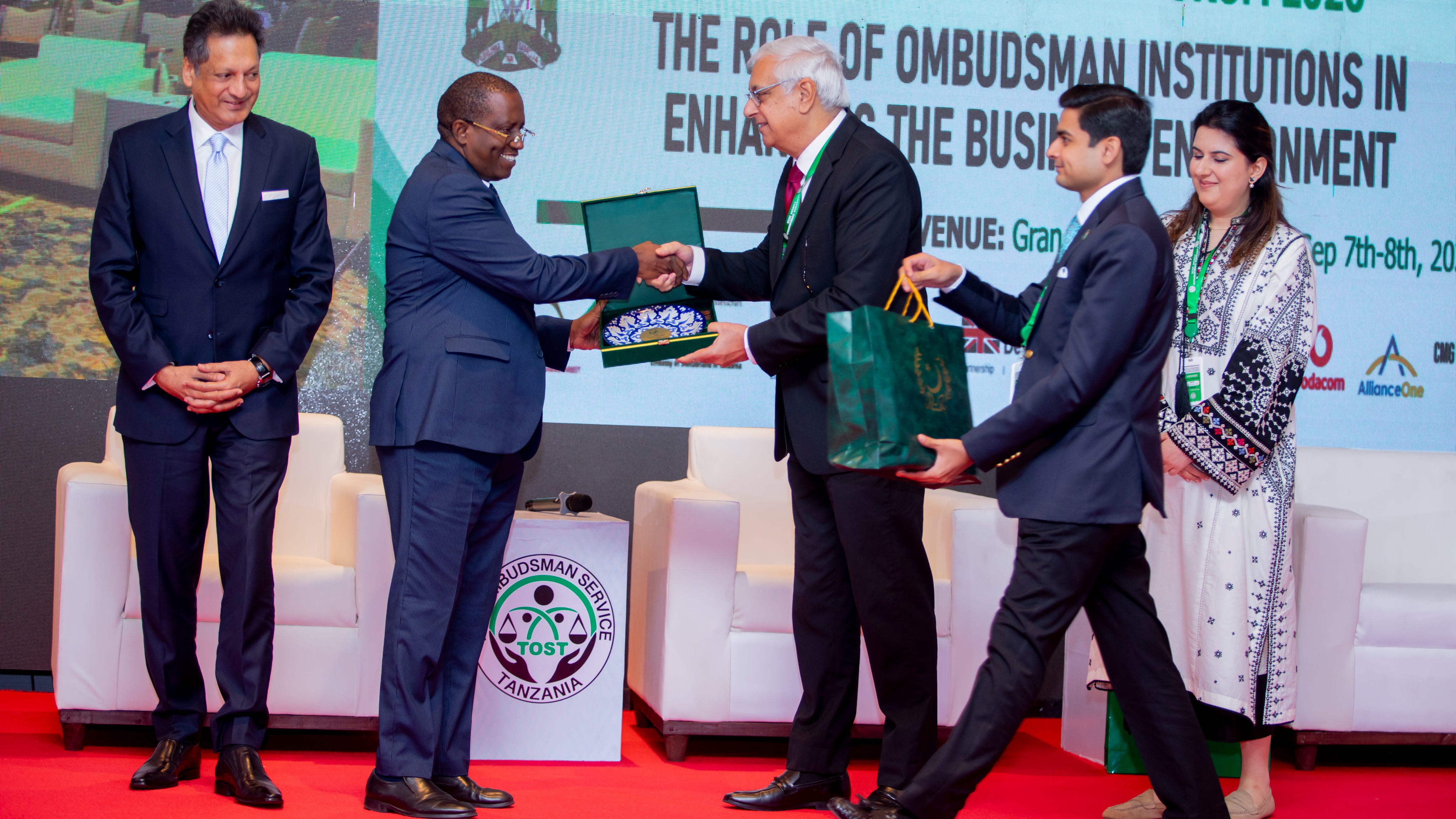 Kaimu wa Kitengo cha Habari na Mawasiliano kwa Umma wa Ofisi ya Usuluhishi wa Malalamiko na Taarifa za Kodi (TOST) akipokea zawadi katika Mkutano wa Masuala ya Usuluhishi (Tanzania Ombudsman Forum 2026), uliofanyika tarehe 7–8 Septemba 2026 katika Hoteli ya Gran Meliá, jijini Arusha.